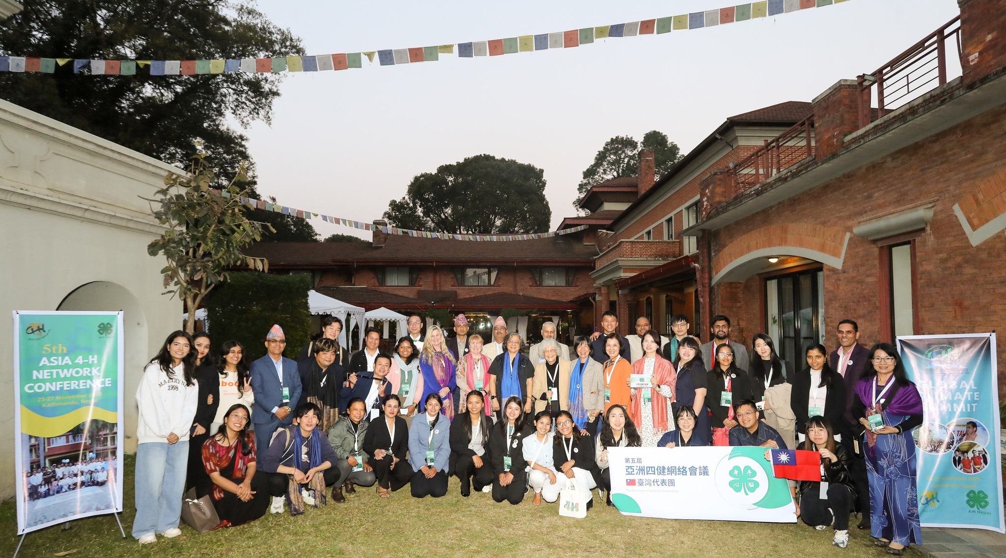 A group of people outside a building with signs that say 5th Asian 4-H Network Conference and Global Climate Summit.